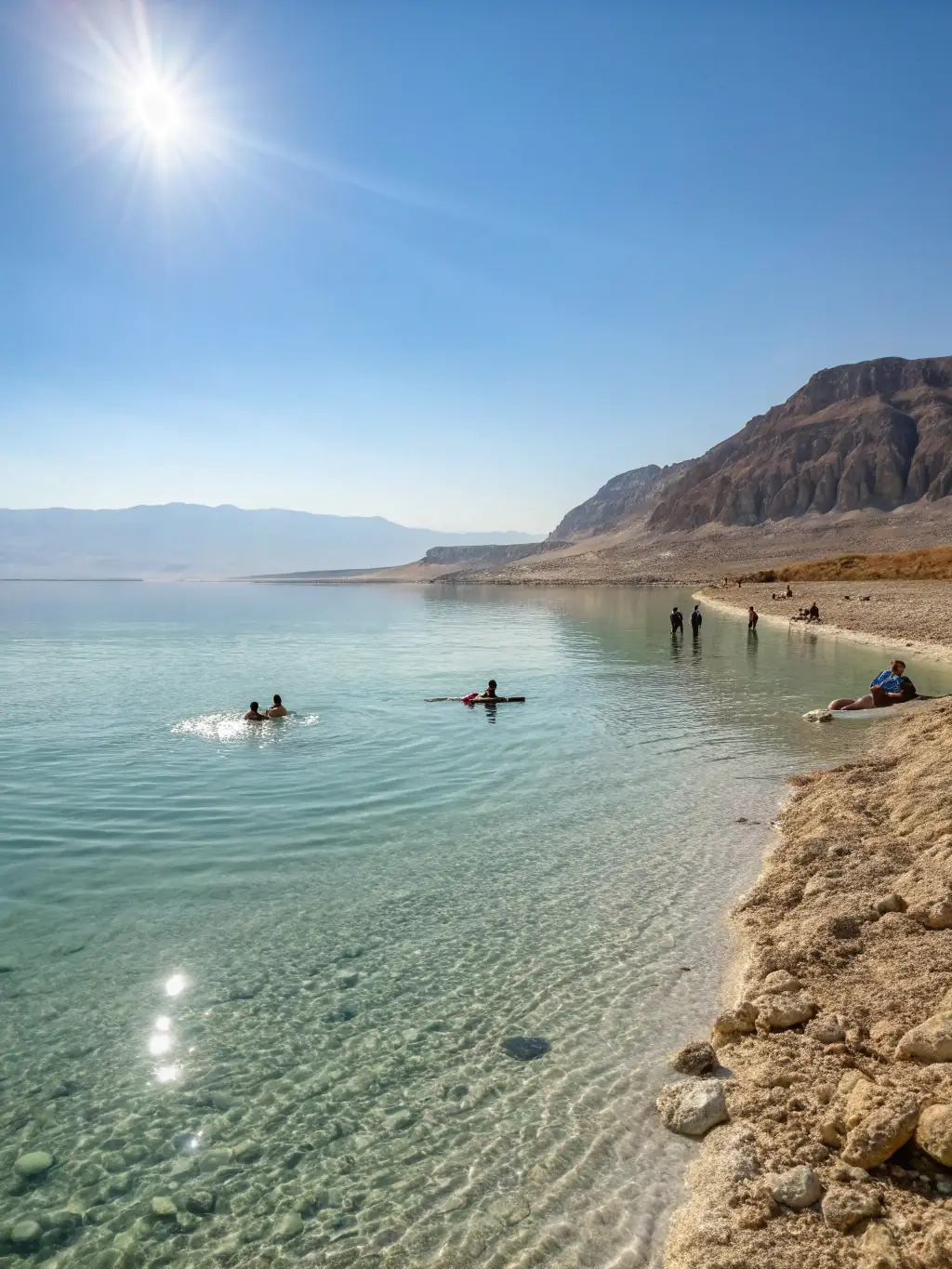 A panoramic view of the Dead Sea, with tourists floating effortlessly in the mineral-rich waters, highlighting the unique and therapeutic experience.